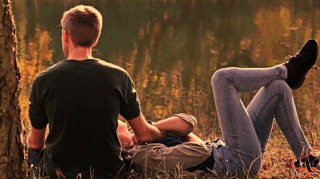 Couple dans une prairie, homme assis de dos et femme allongé avec la tête sur la cuisse de l'homme