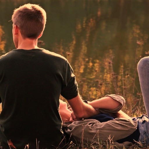 Couple dans une prairie, homme assis de dos et femme allongé avec la tête sur la cuisse de l'homme